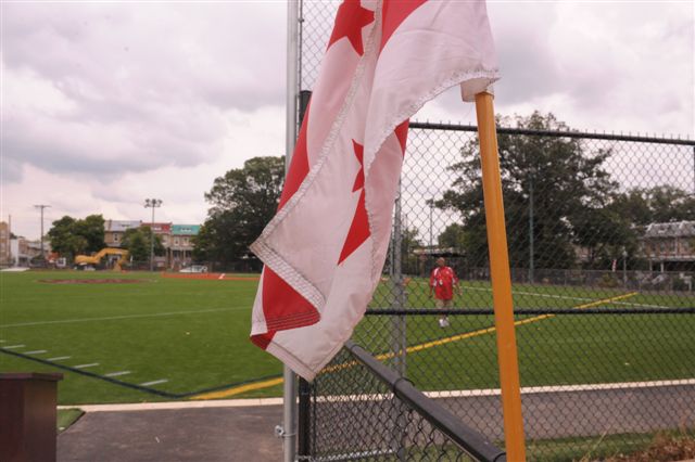 a red and white canadian flag hanging in front of a fence