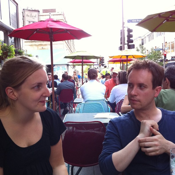 two people at an outdoor restaurant eating and drinking