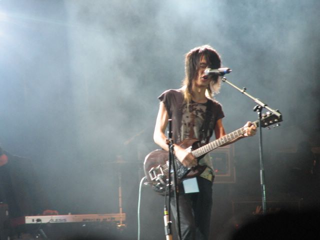 the young guitarist stands near a microphone as he plays his guitar