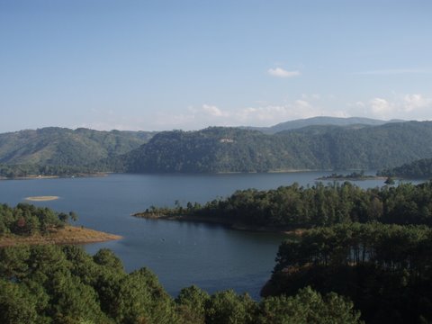 a mountain lake with trees and hills in the distance