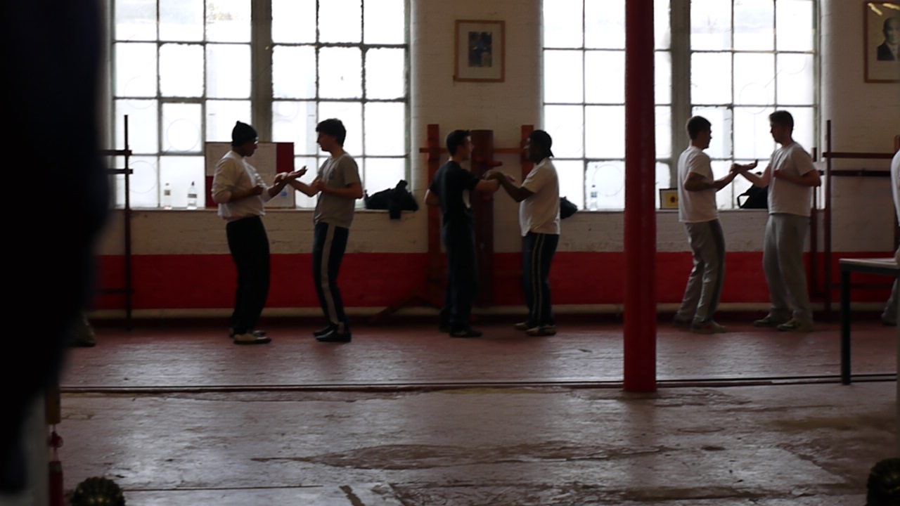 men standing by some big windows using their cell phones