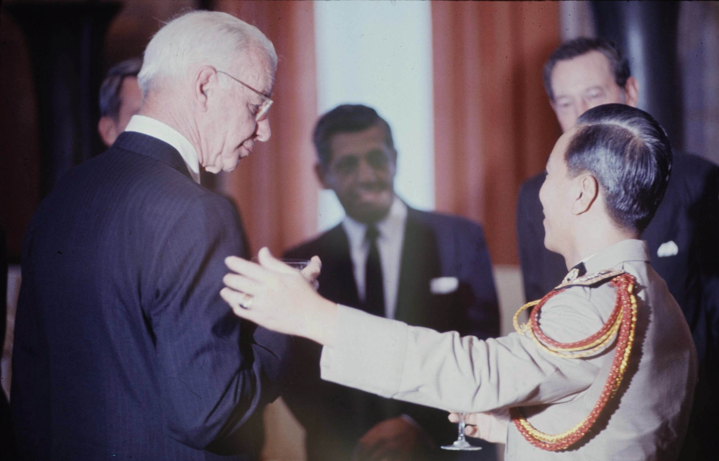 older man in suit shaking hands with younger man in tie