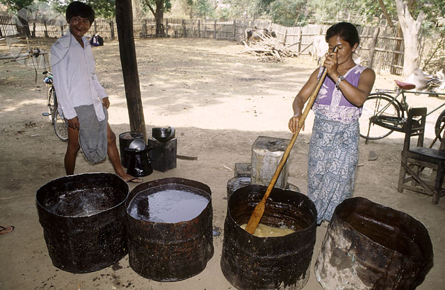 a woman stirring some white liquid in wooden buckets