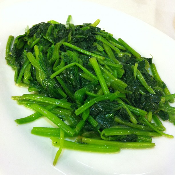 a plate filled with green vegetables and sliced peppers