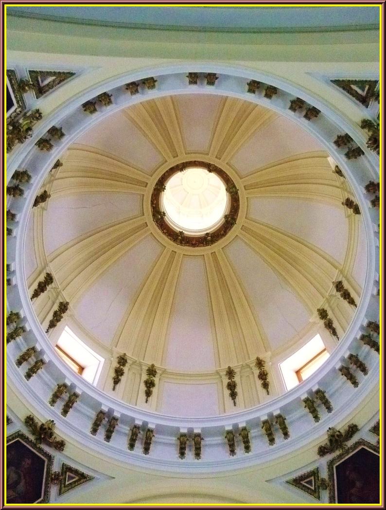 looking up at a domed white ceiling with two high windows