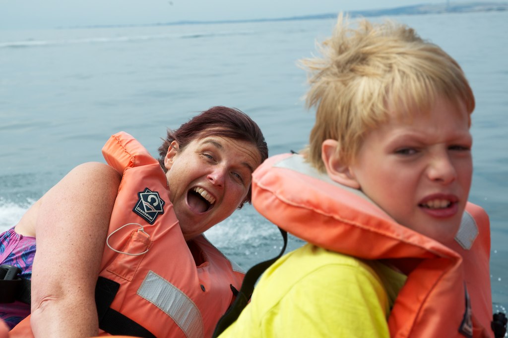 two boys in life jackets on the back of a boat