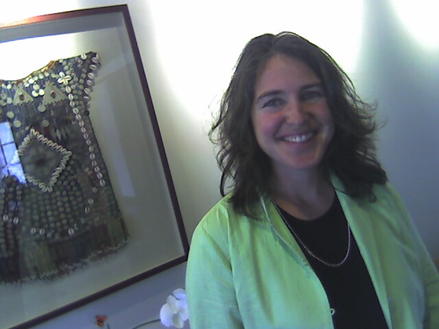 a woman smiles in front of a painting in the background