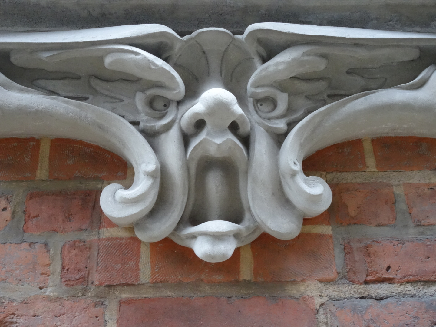 a gargoyle on a brick building with two wings in the center