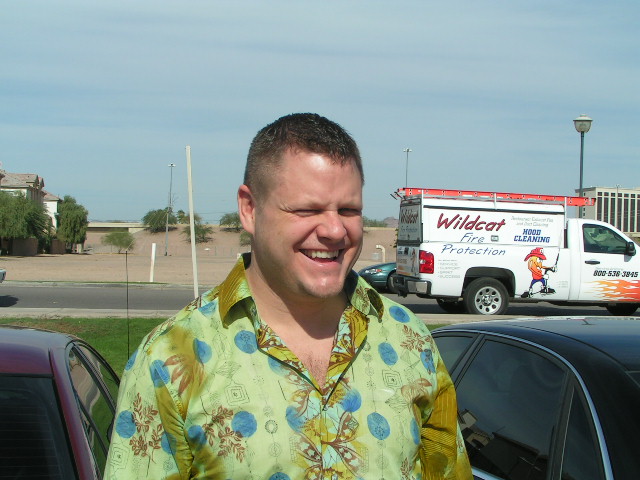 a man smiling at the camera in front of a truck