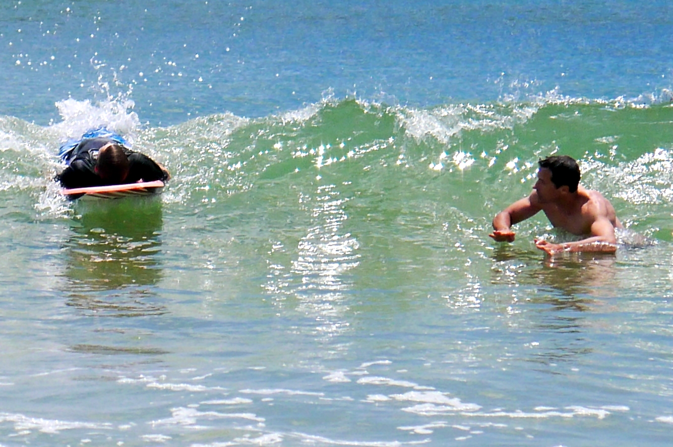 a man standing in the ocean near a small boat