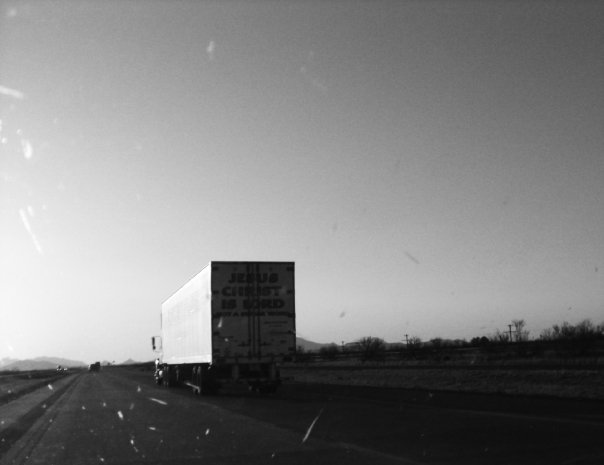 black and white pograph of semi truck traveling down a highway