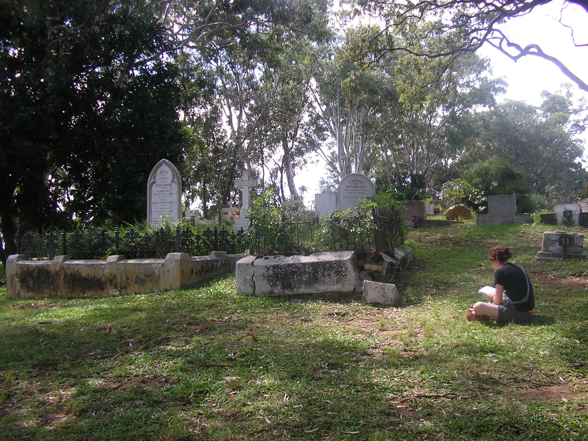 a man is sitting in front of a grave yard