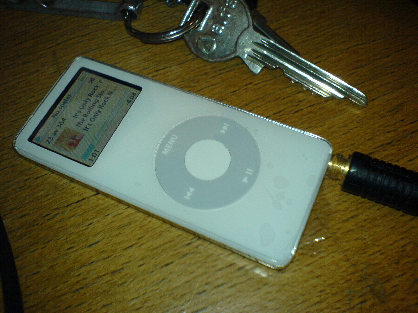 an ipod sits on a table with a keyshelf behind it