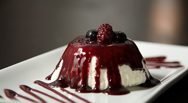 a cheesecake with berries on top of it sits on a plate