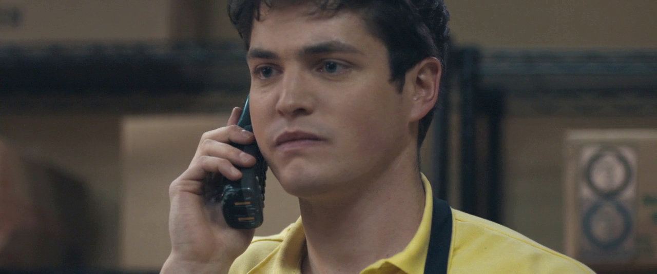 a young man wearing yellow shirt talking on phone