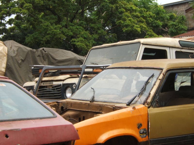 several old and broken cars in front of trees