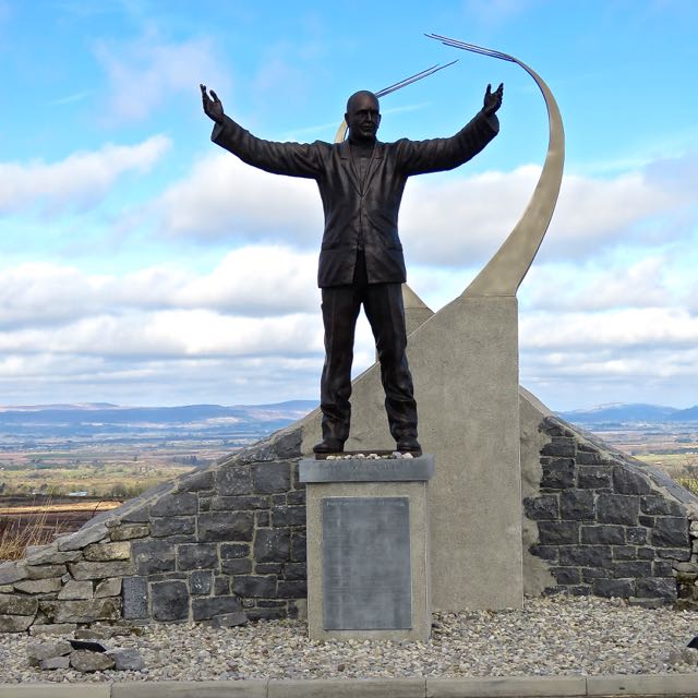 a statue of a man with his arms outstretched holding a pole