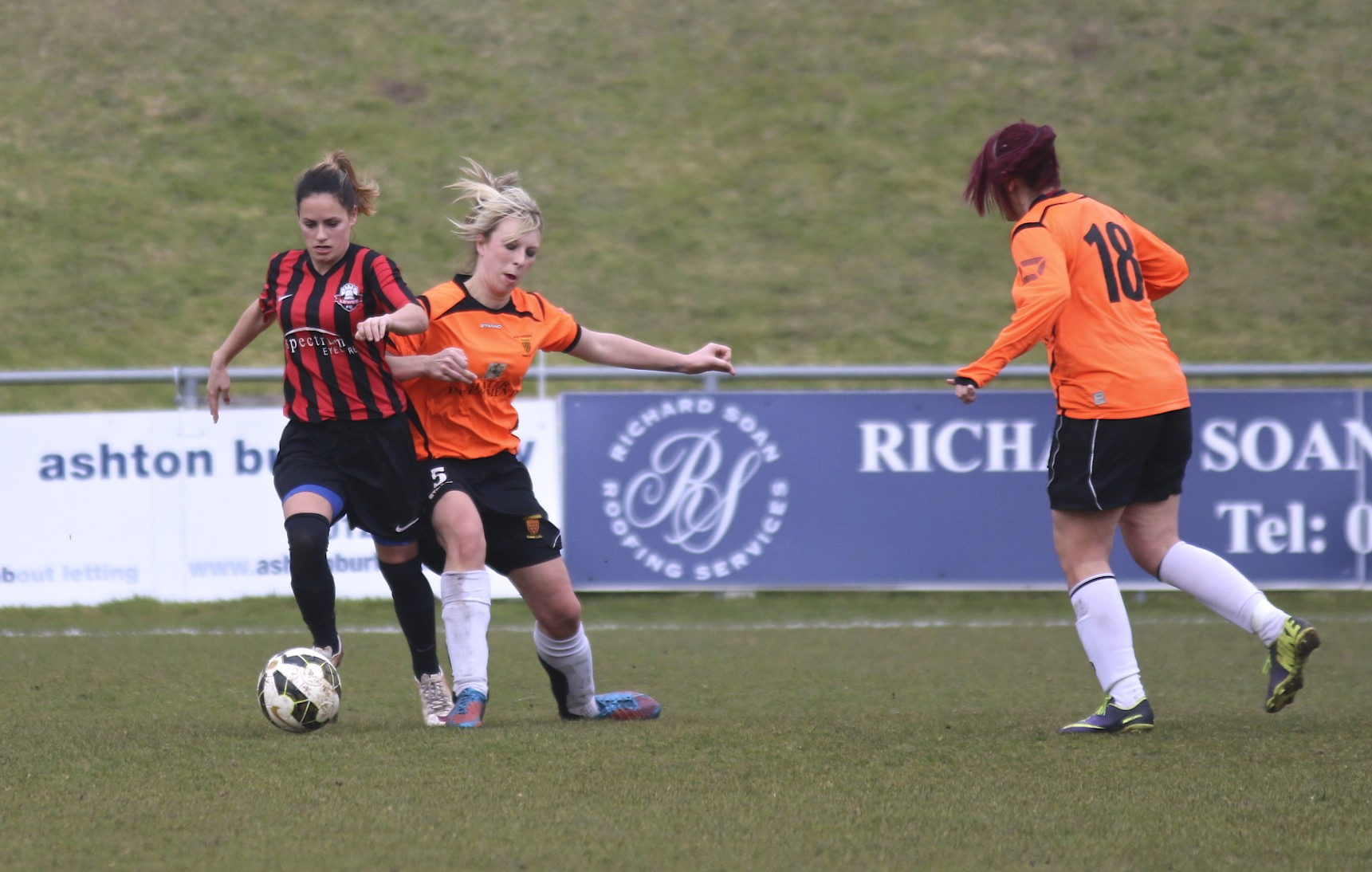 girls in uniforms kicking a soccer ball around