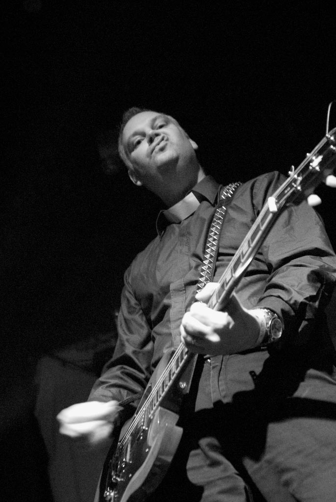 a man playing a guitar on stage with his mouth open