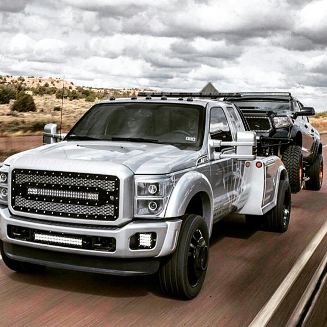 a silver truck drives down the highway beside an open truck