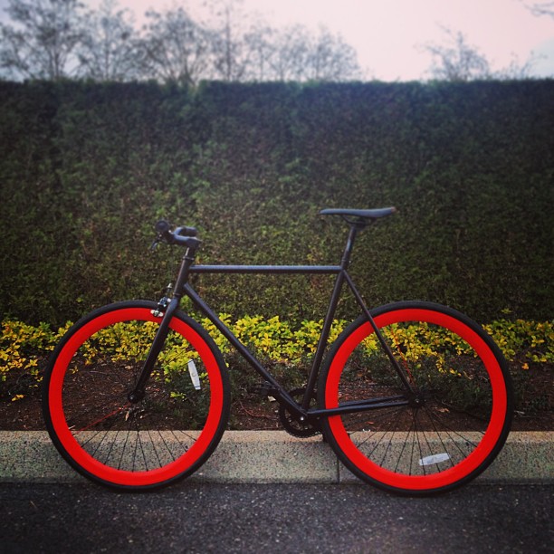 there is a bike with a red tire in front of a hedge