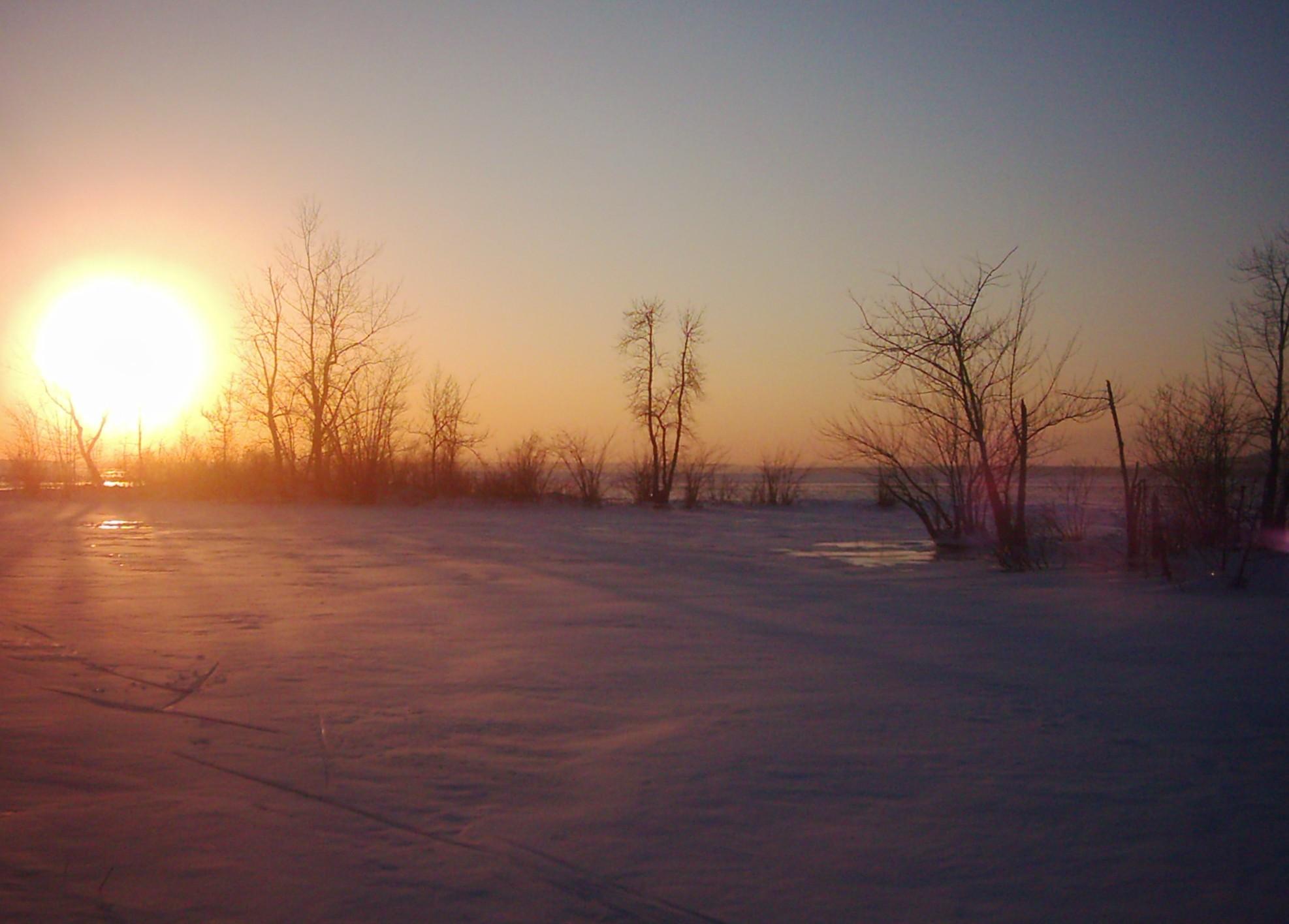 a person with skis standing in the snow with the sun setting