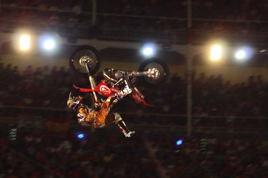 a person riding a motorcycle performing a trick in front of an audience