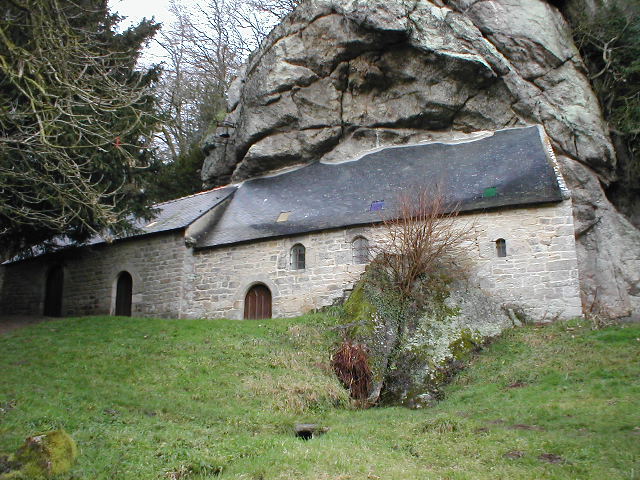a rock - covered building sits atop a grassy hill