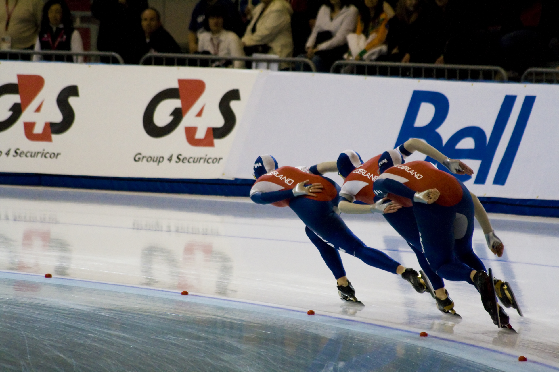 a group of three men skating on ice in a rink
