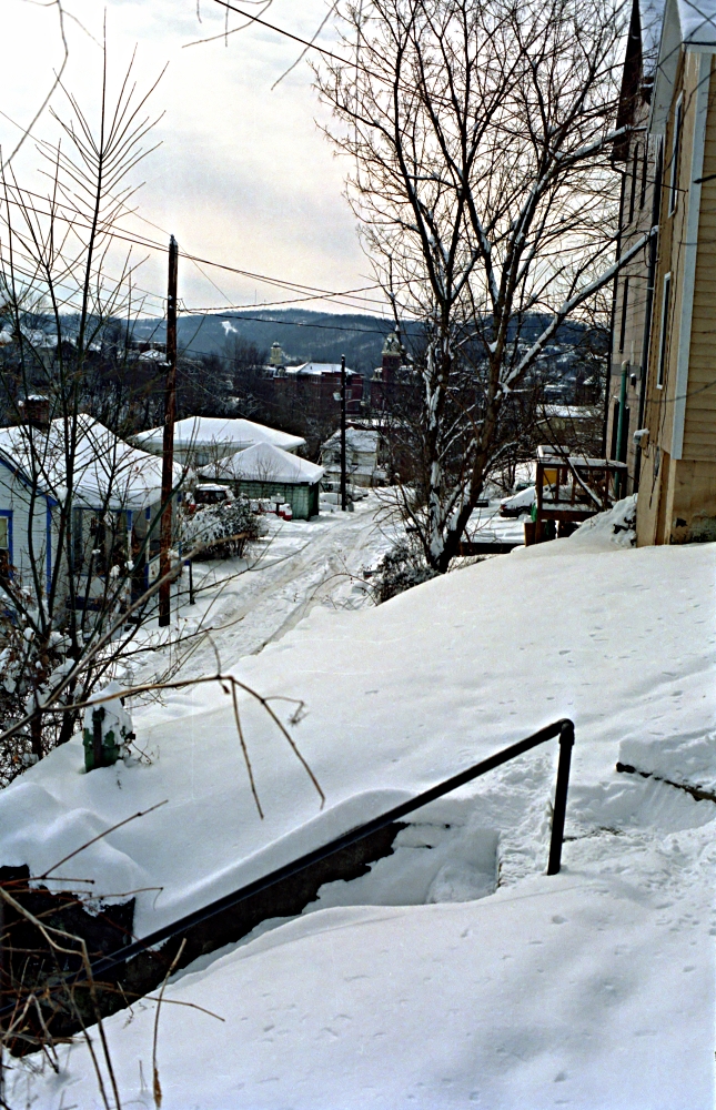 snow covered path and residential houses by the water