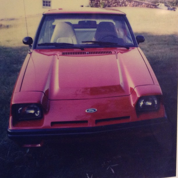 a po of a car on grass with a house in the background