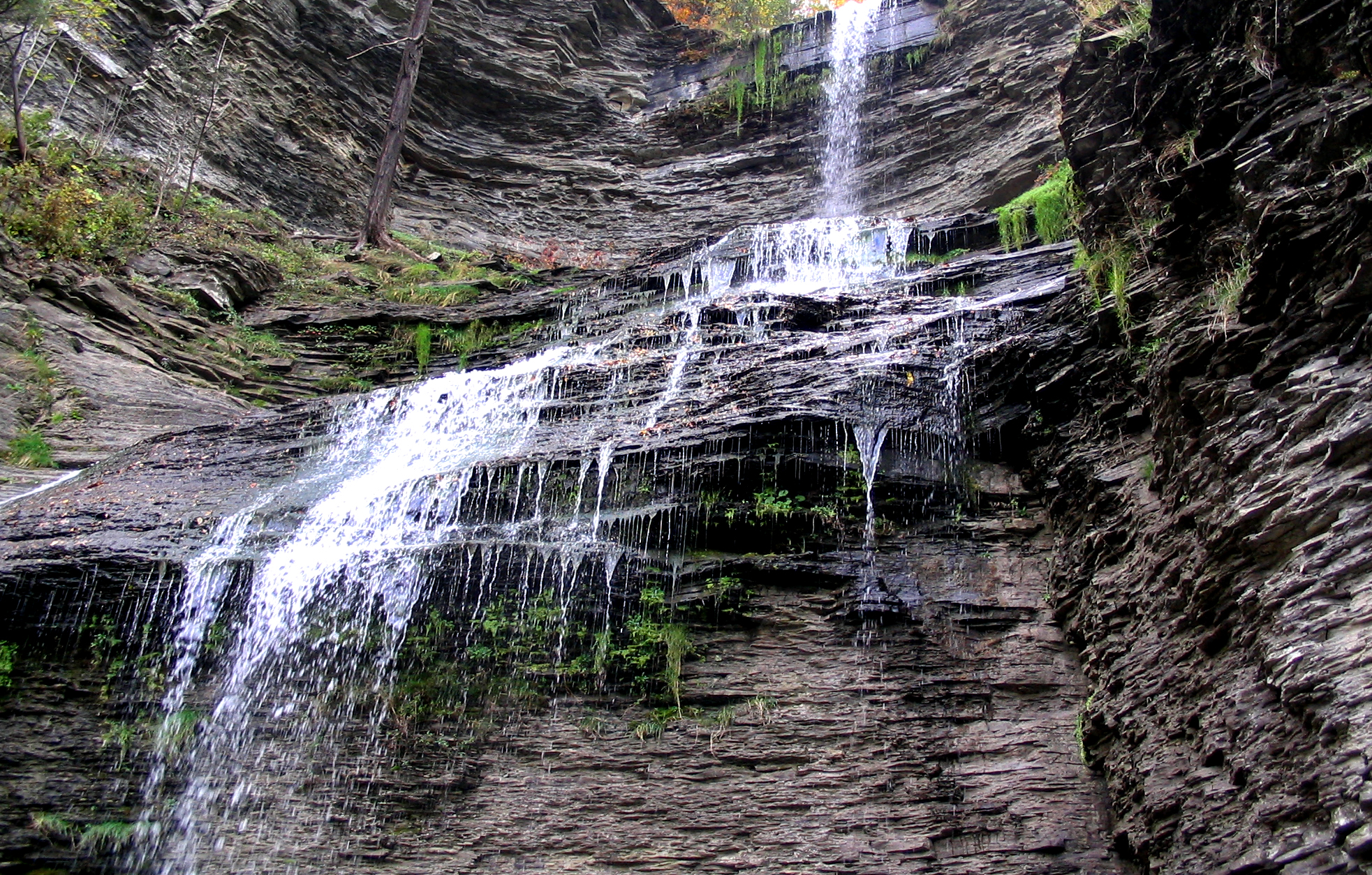 a beautiful waterfall running into a gorge with a bench under it