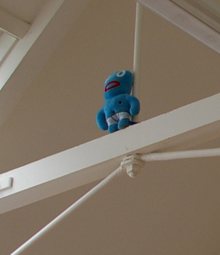 a blue stuffed animal is perched on the support of a beam