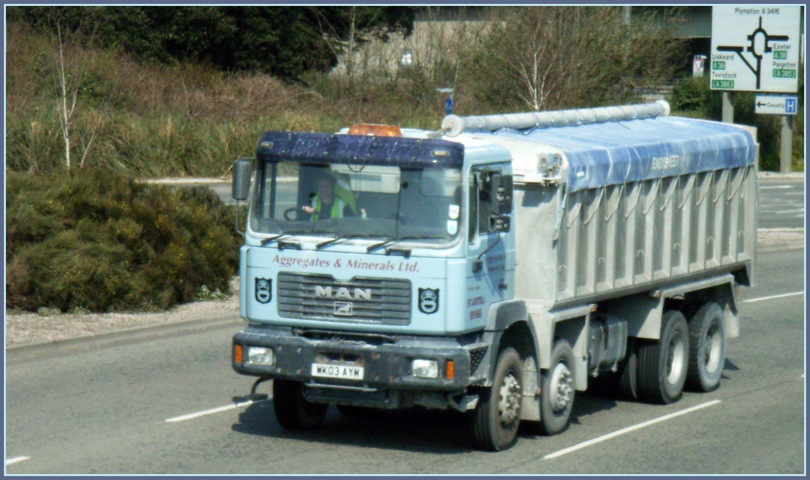 a dump truck driving down a street with trees on both sides