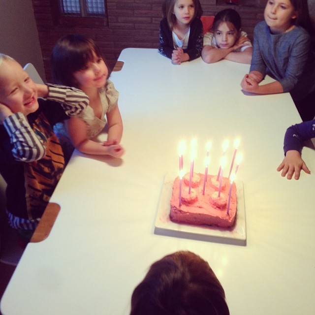 children sitting around a table with a birthday cake