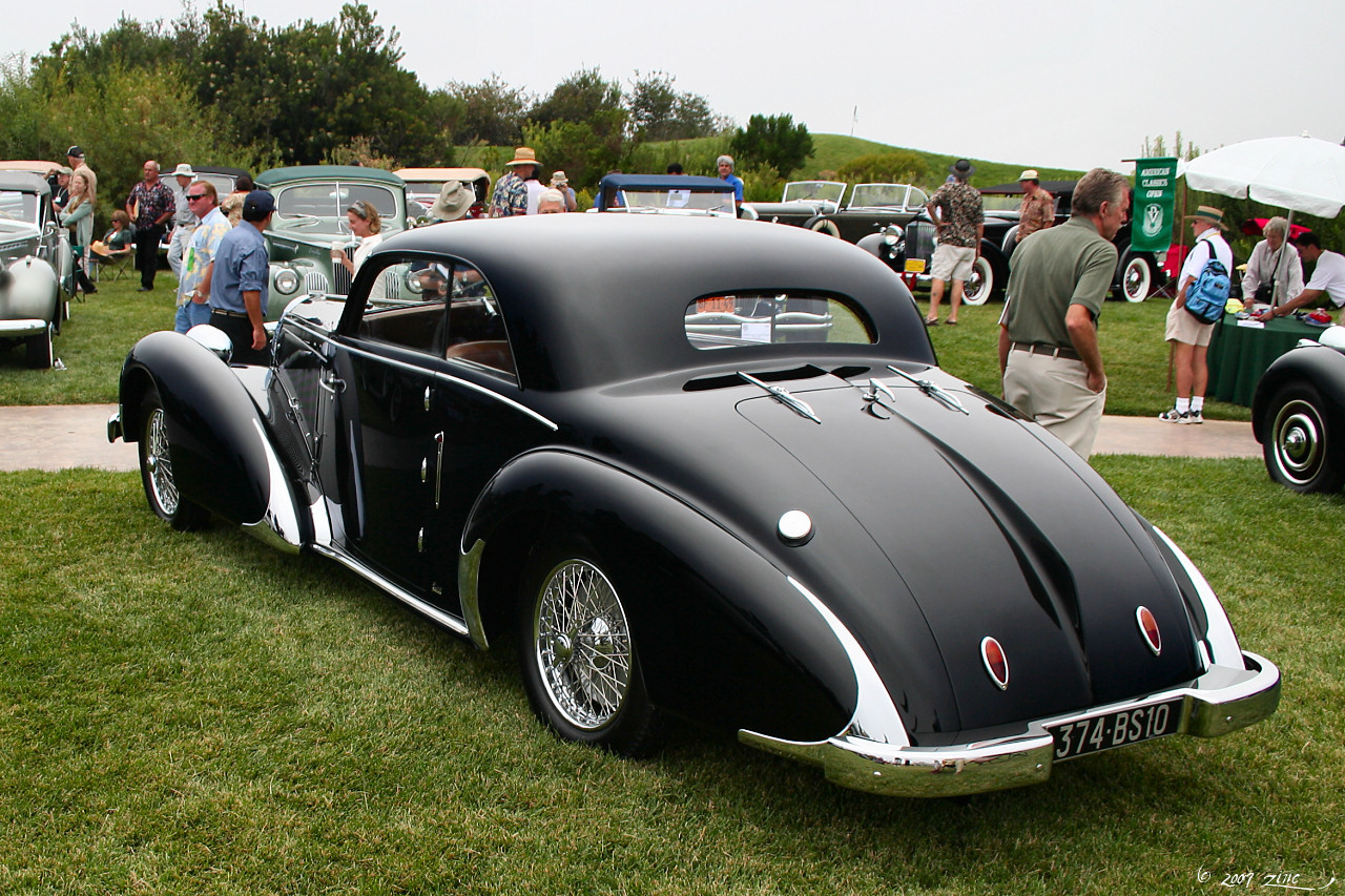 an antique black car is parked in the grass