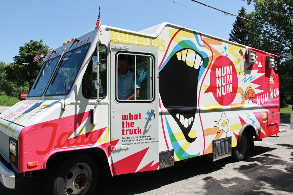 a white food truck with various colorful advertits