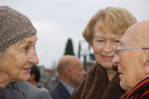 two women are talking to an old man who is wearing glasses