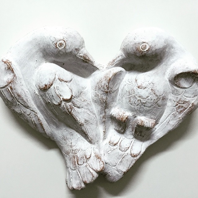 a white sculpture of two birds and a heart