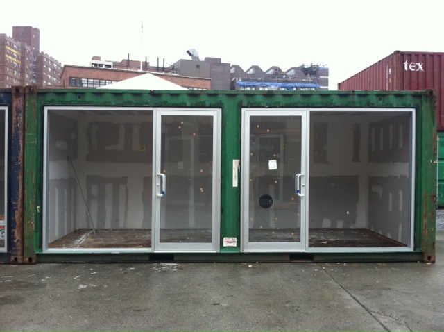 a large green shipping container with three glass doors