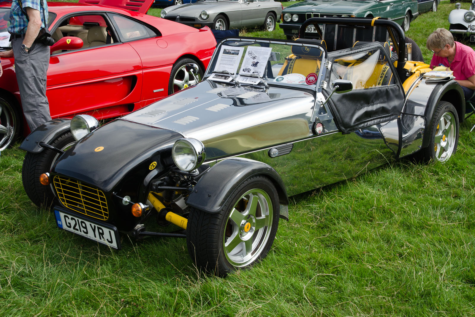 people looking at antique cars in a field