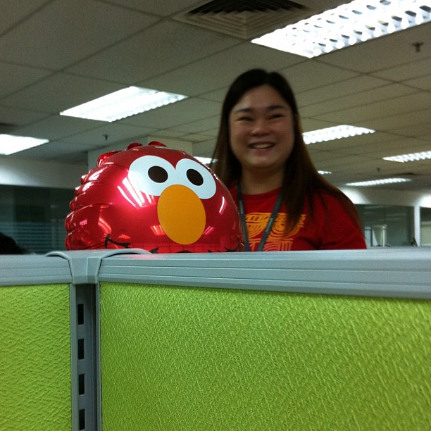 a girl is smiling for the camera next to a big red bird balloon