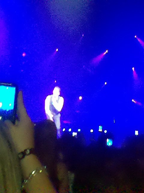 man standing on stage on his phone with his arms crossed