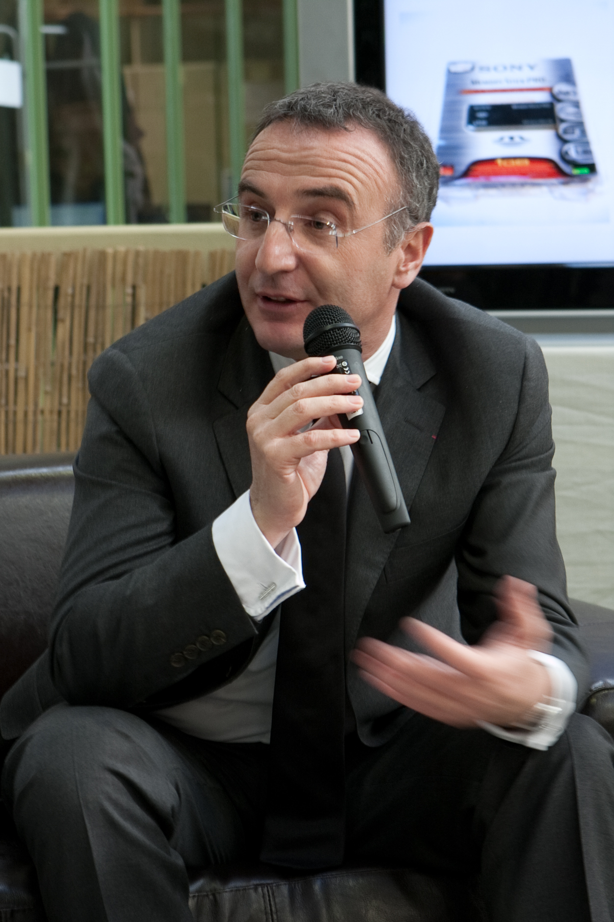 a man in a suit talks into a microphone