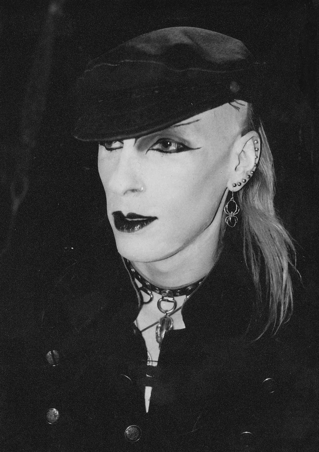 woman with makeup wearing a black hat and stud earrings