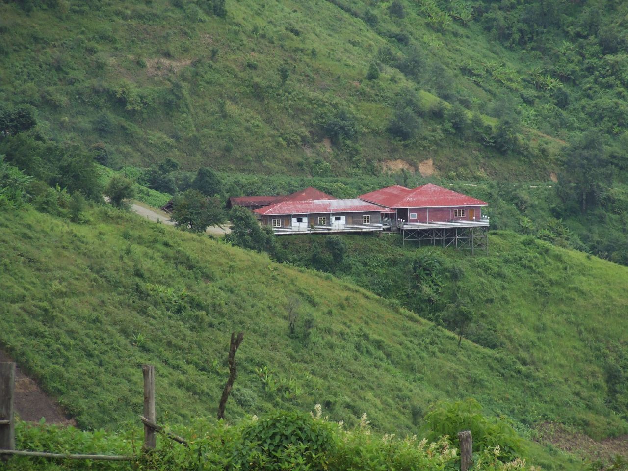 a green hillside with a house sitting in the middle