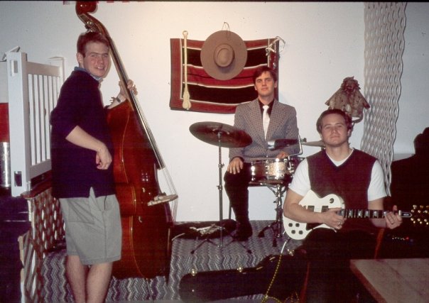 there are three men playing instruments in a room