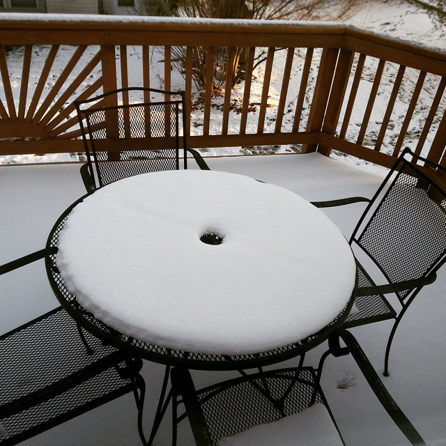 an outdoor table and chair covered in snow
