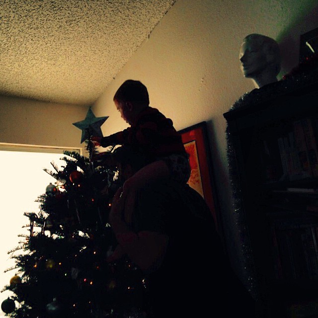 a boy standing near a christmas tree in his living room