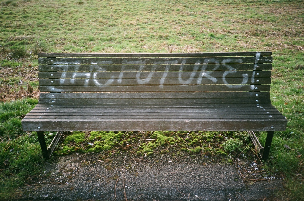 a park bench sitting in front of a grass covered field